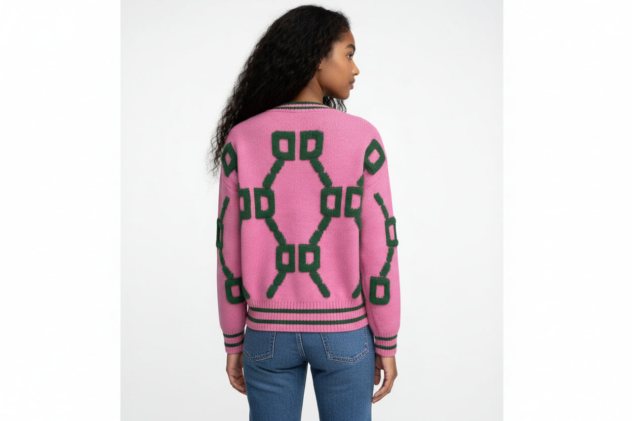 Person wearing a pink sweater with green geometric patterns on a white background