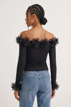Elegant off-the-shoulder top in a soft black hue is crafted from a smooth, form-fitting fabric with delicate ruching along the torso that accentuates the silhouette. 
