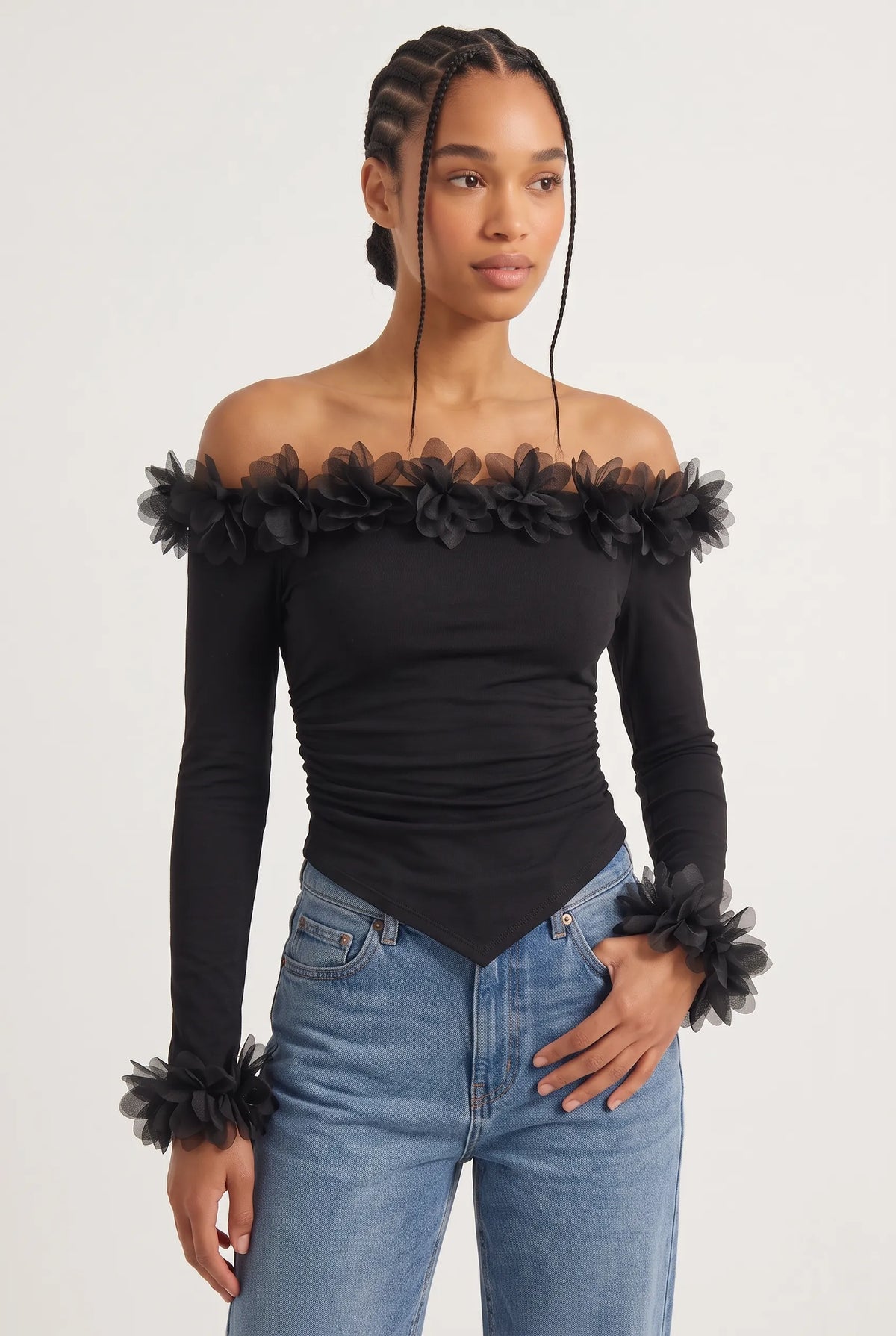 Elegant off-the-shoulder top in a soft black hue is crafted from a smooth, form-fitting fabric with delicate ruching along the torso that accentuates the silhouette. 