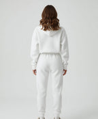 Person wearing a white hoodie and pants set on a plain background