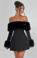 Black off-shoulder dress with fur trim worn by a model on a gray background