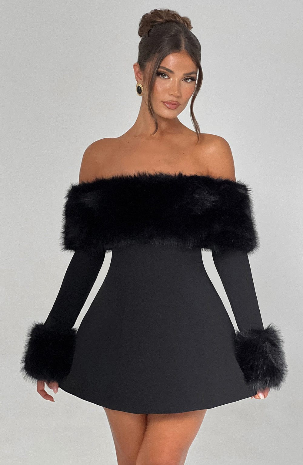 Black off-shoulder dress with fur trim worn by a model on a gray background