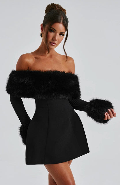 Woman wearing a black dress with fur accents against a gray background