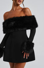 Black off-shoulder dress with fur accents on a plain background