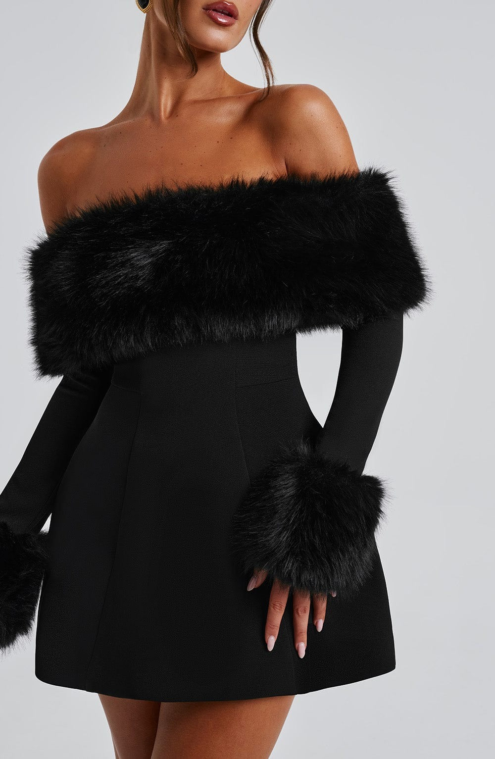 Black off-shoulder dress with fur accents on a plain background