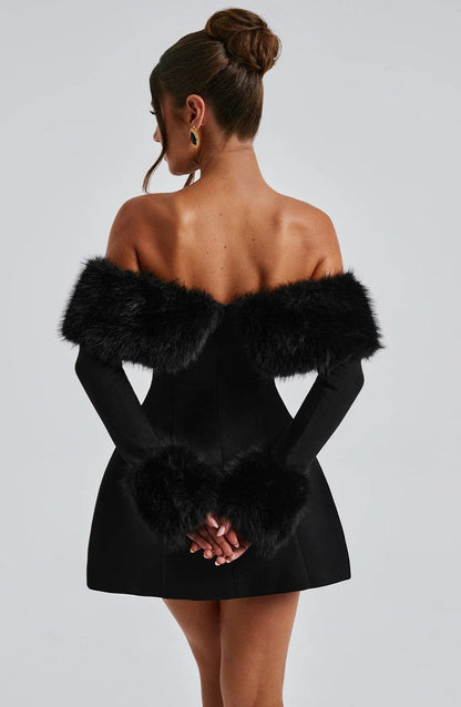 Black dress with fur trim worn by a model on a plain background