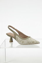 Beige slingback shoe with floral embellishments on a clear stand