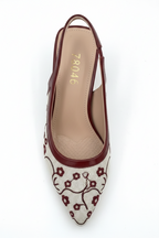 White shoe with floral pattern and maroon heel on a white background