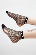 Black fishnet socks with pearl accents worn by a person on a white background