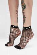 Black fishnet socks with pearl accents worn by a person with tattoos on a white background