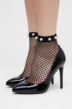 Black fishnet stockings with pearl accents worn by a person with tattoos on a white background