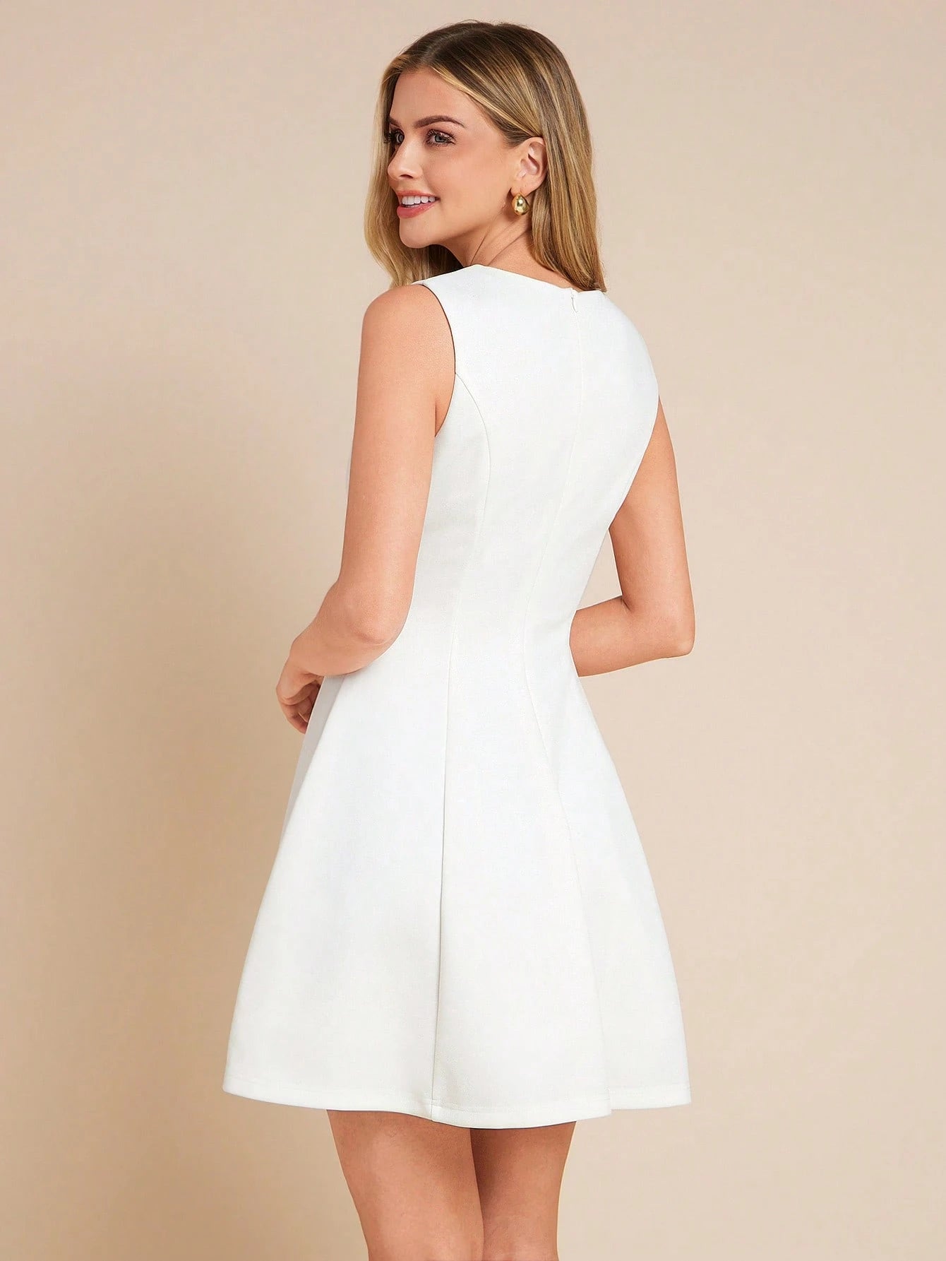 Woman wearing a white dress against a beige background