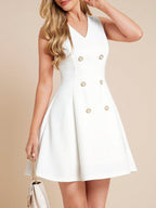 White dress with gold buttons worn by a person on a beige background
