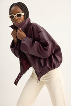 Person wearing a purple jacket and white pants on a plain background