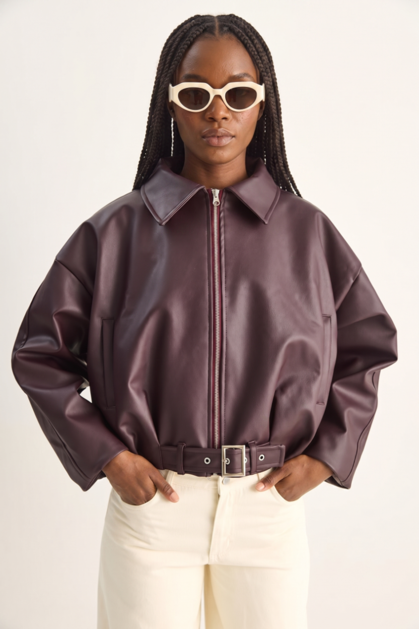 Person wearing a brown leather jacket and sunglasses on a white background