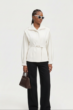 Woman wearing a white jacket and black pants with sunglasses on a white background