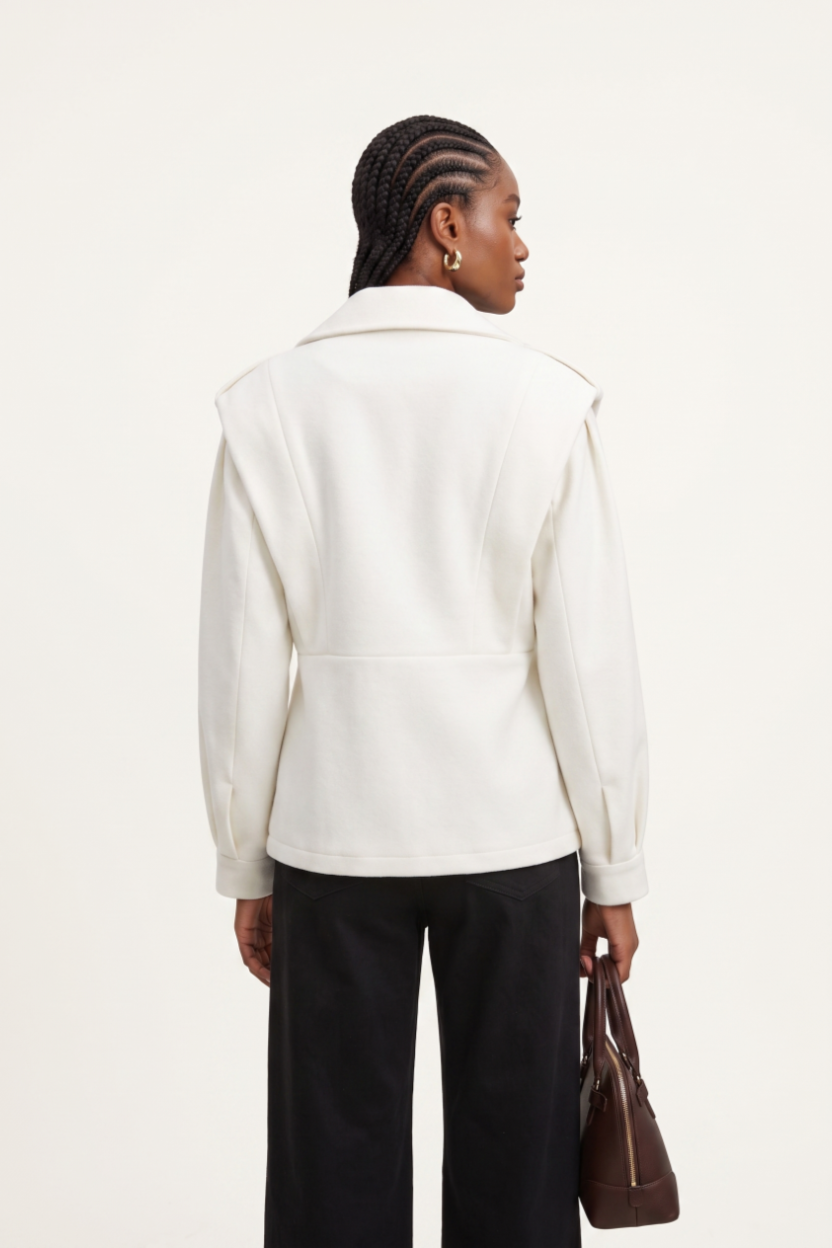 Person wearing a white jacket and black pants holding a brown bag on a white background