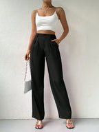 Person wearing a white crop top and black high-waisted pants against a plain background