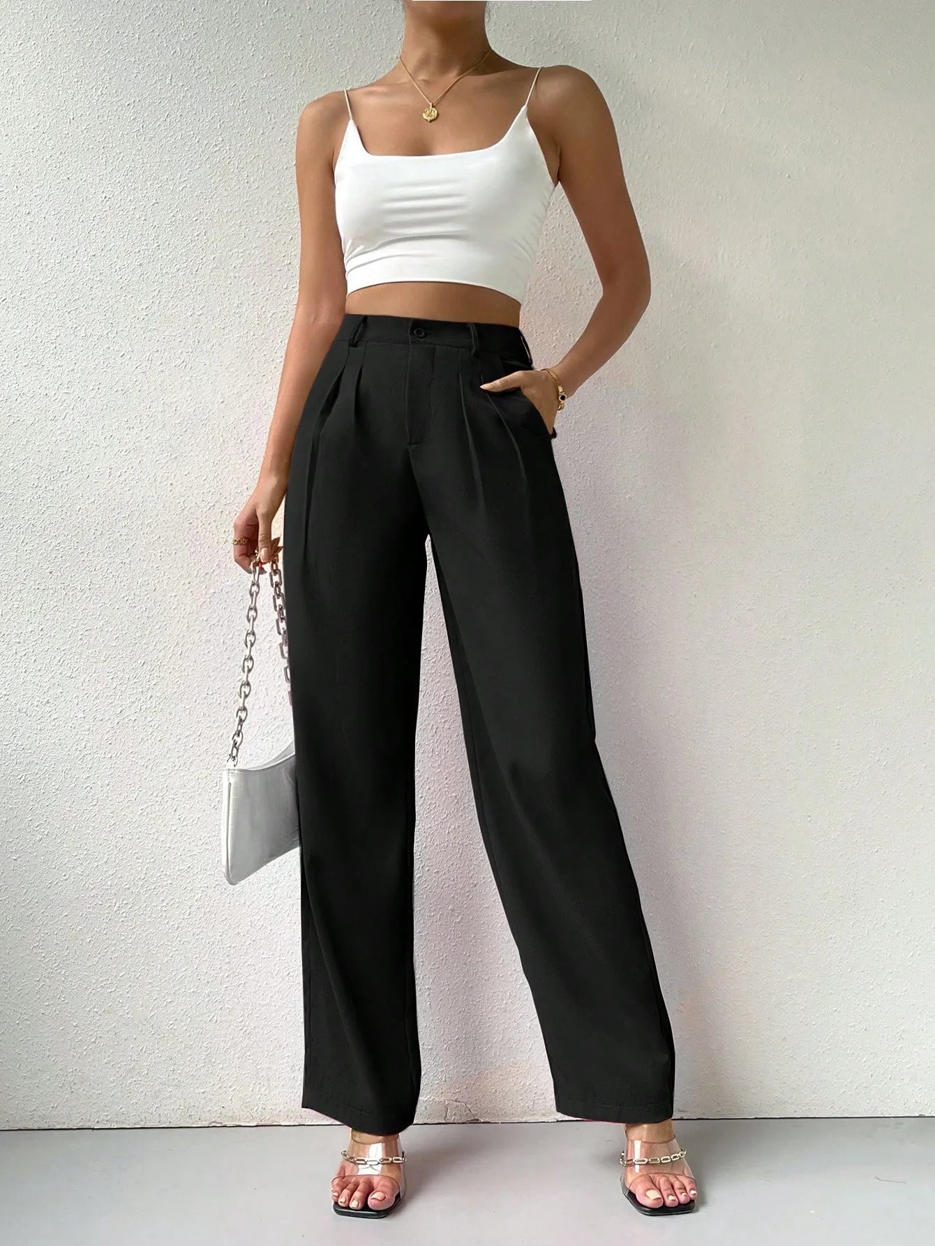 Person wearing a white crop top and black high-waisted pants against a plain background