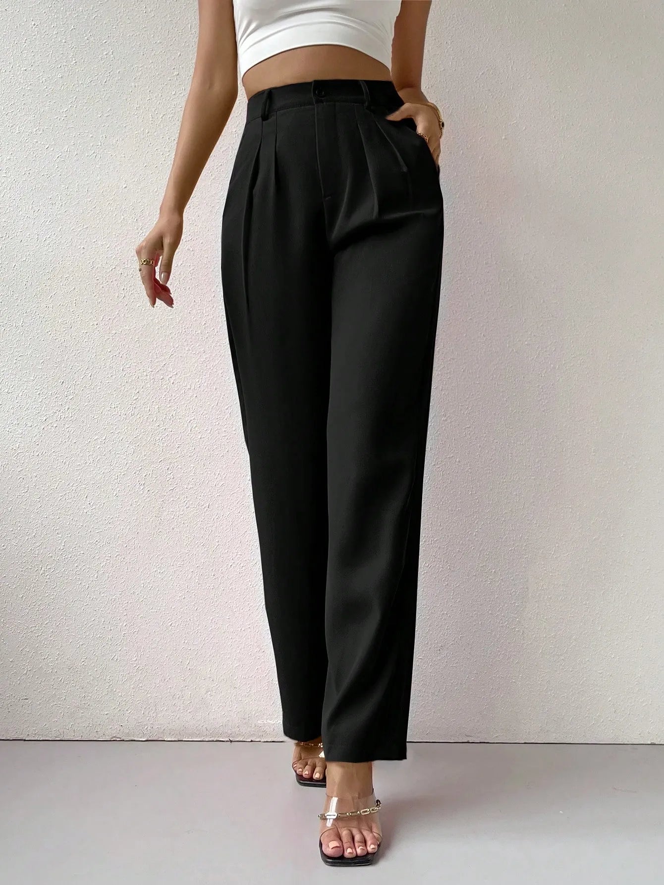 Person wearing black high-waisted pants against a plain background