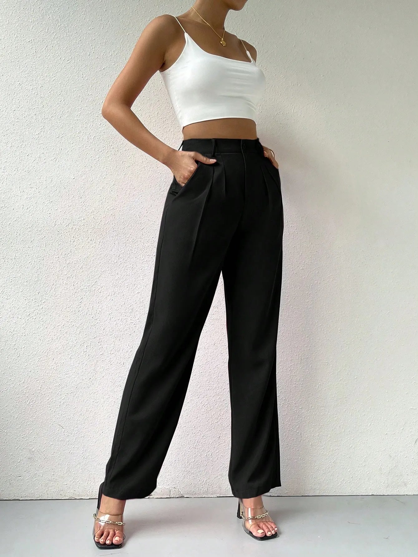 Person wearing a white crop top and black wide-leg pants against a light background