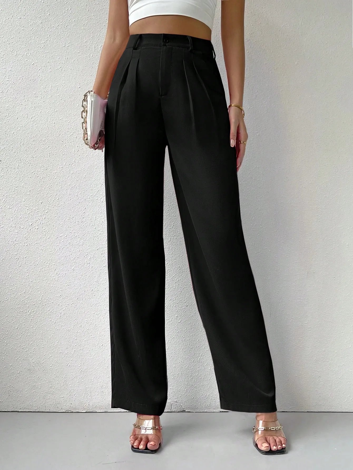 Person wearing black high-waisted pants on a plain background