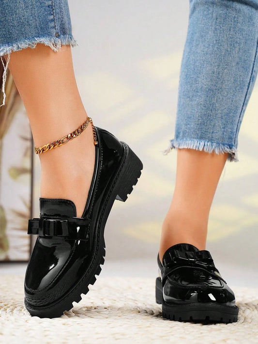 Black glossy shoes worn with denim jeans on a blurred background