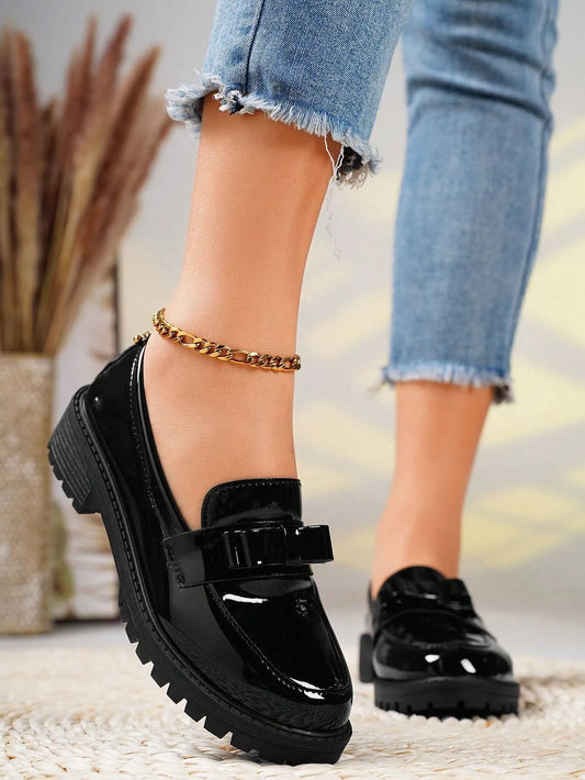 Black platform shoes worn with light blue jeans on a blurred background