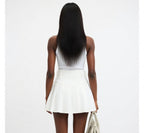 Person wearing a white top and skirt on a plain background