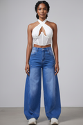 Woman wearing a white halter top and blue jeans against a gray background