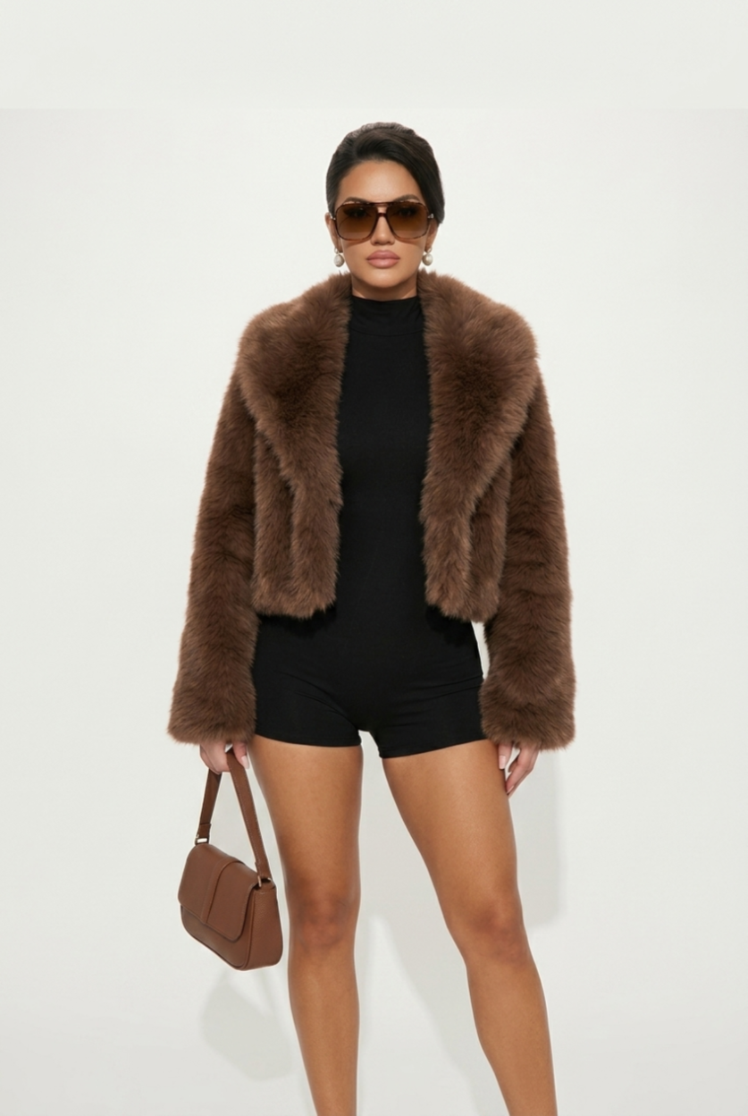 Person wearing a brown fur coat, black outfit, and sunglasses on a white background