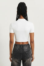 a woman wearing a white, short-sleeved, zip-front crop top paired with dark-washed jeans