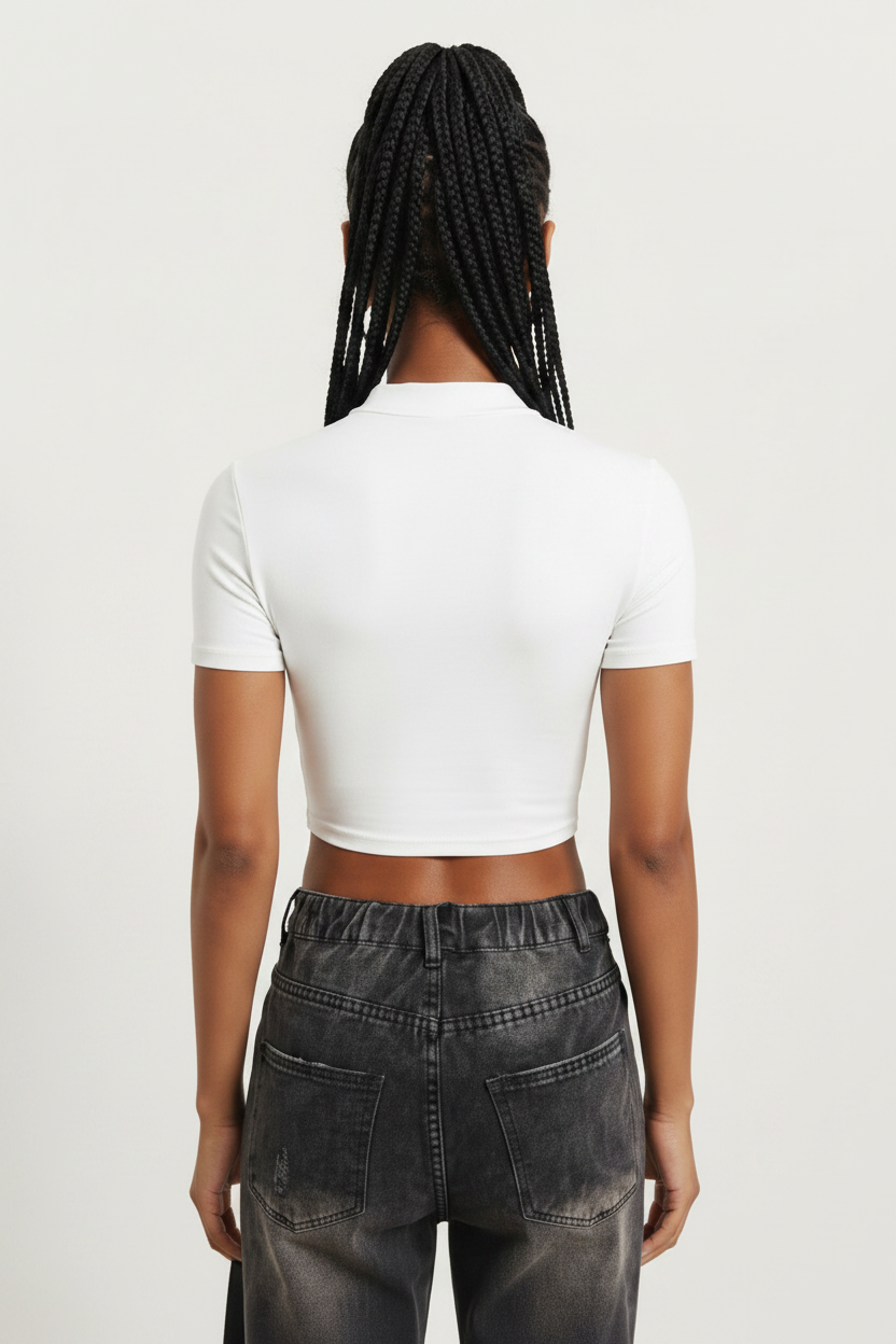 a woman wearing a white, short-sleeved, zip-front crop top paired with dark-washed jeans