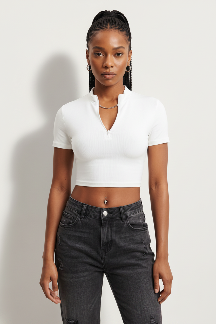 a woman wearing a white, short-sleeved, zip-front crop top paired with dark-washed jeans