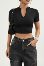 a woman wearing a black, short-sleeved, zip-front crop top paired with dark-washed jeans