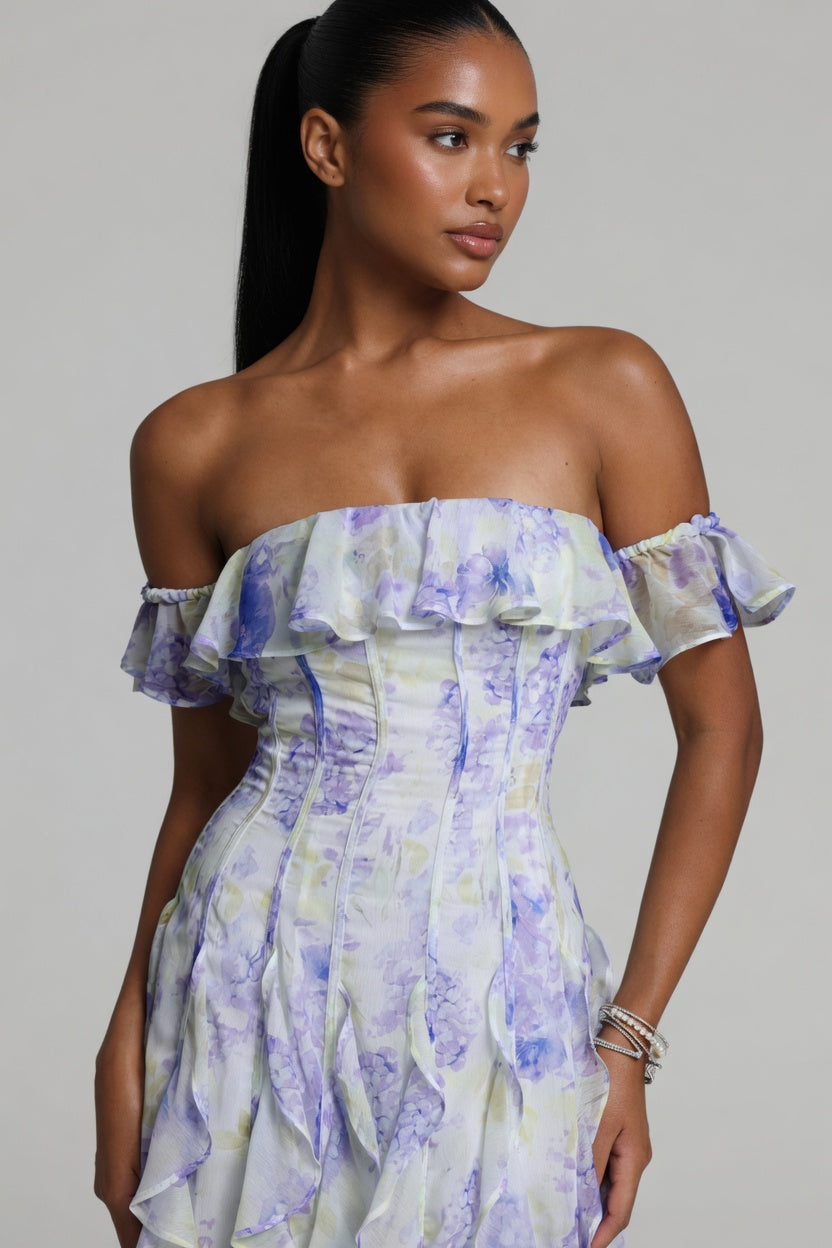 Woman wearing a floral off-shoulder dress against a gray background
