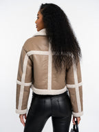 Woman wearing a beige and white jacket with black pants on a white background