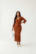 Woman wearing a brown ribbed dress with long sleeves in a bright room.
