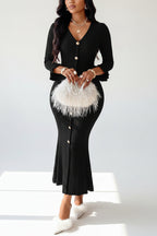 Woman wearing a black ribbed dress with a white feathered clutch against a white background