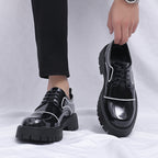 Black platform shoes with white accents worn by a person on a light gray background