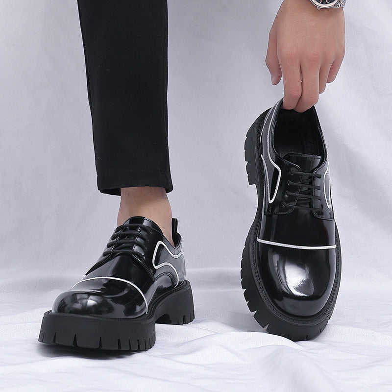 Black platform shoes with white accents worn by a person on a light gray background