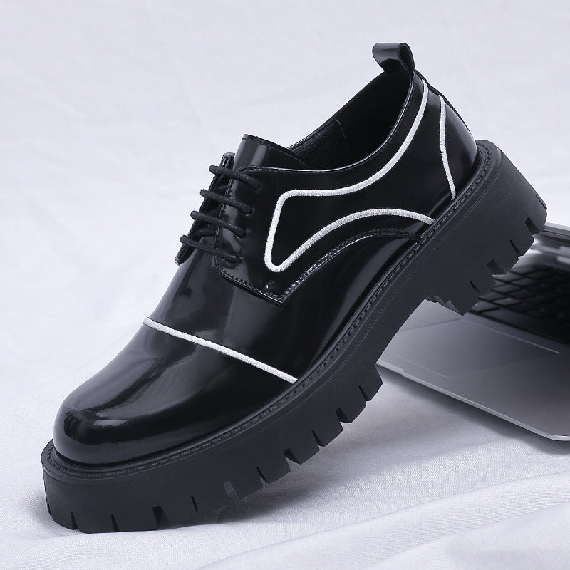 Black glossy shoes with white accents on a white fabric background