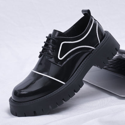 Black glossy shoes with white accents on a white fabric background