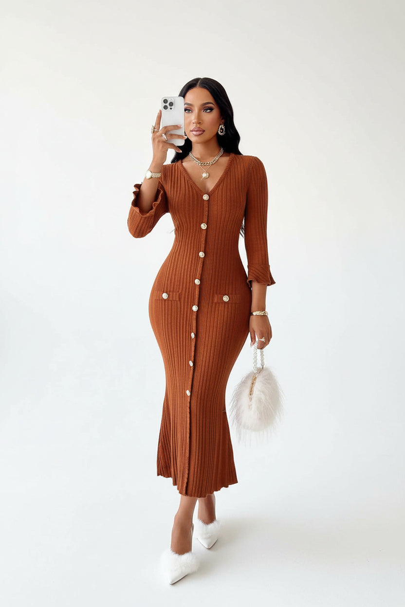Woman in a brown ribbed dress taking a selfie in a bright room with large windows.