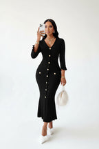 Woman wearing a black ribbed dress holding a phone on a white background