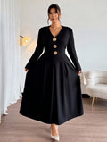 Woman wearing a black dress with gold buttons in a room with a white sofa and lamp.