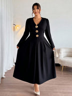 Woman wearing a black dress with gold buttons in a room with a white sofa and lamp.