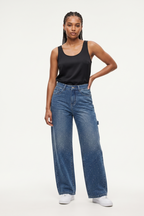 Woman wearing a black tank top and blue jeans on a white background