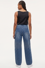 Person wearing blue jeans and a black top on a white background