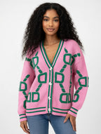 Woman wearing a pink cardigan with green geometric patterns on a white background